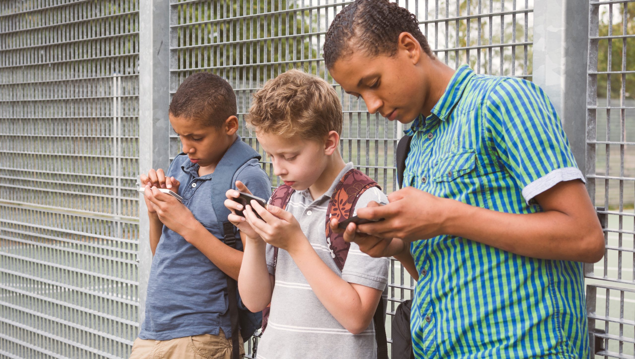 Three boys after school using their smartphone.